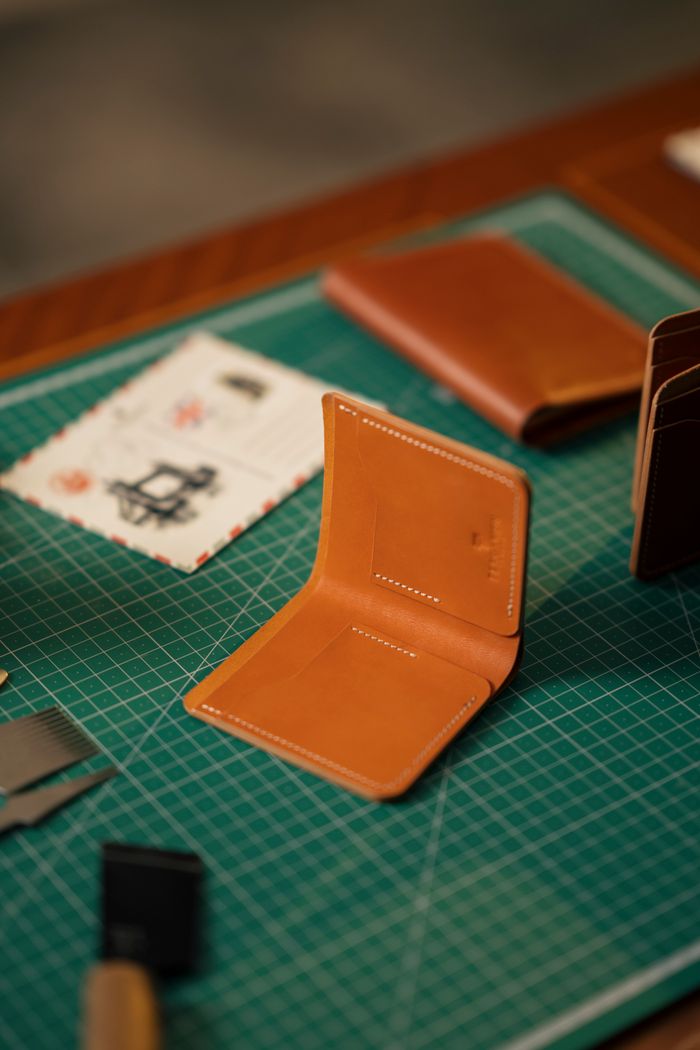 collection-05 Close-up of handcrafted leather wallets on a green cutting mat, showcasing craftsmanship and design.