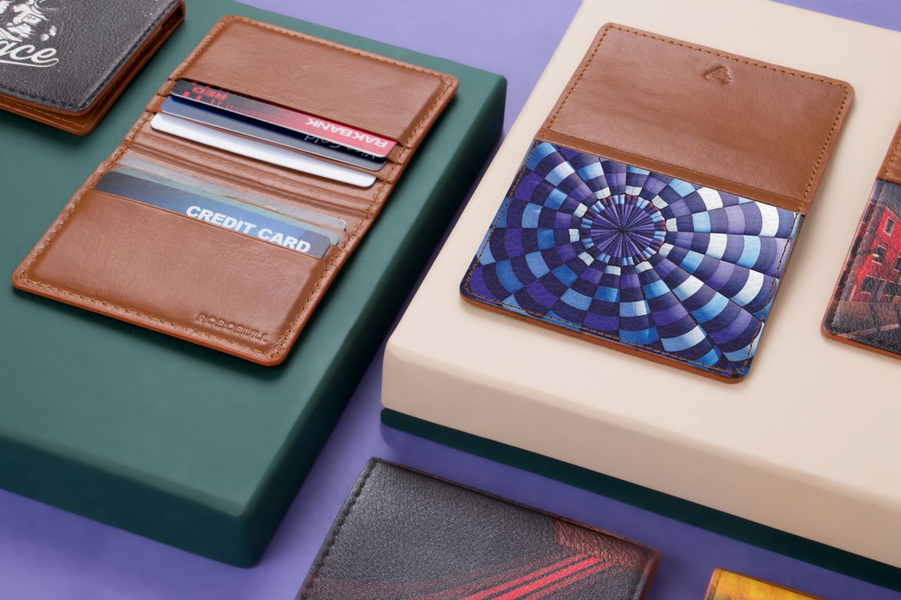 summer-sale Close-up of assorted leather wallets and cardholders on a modern violet and green background.